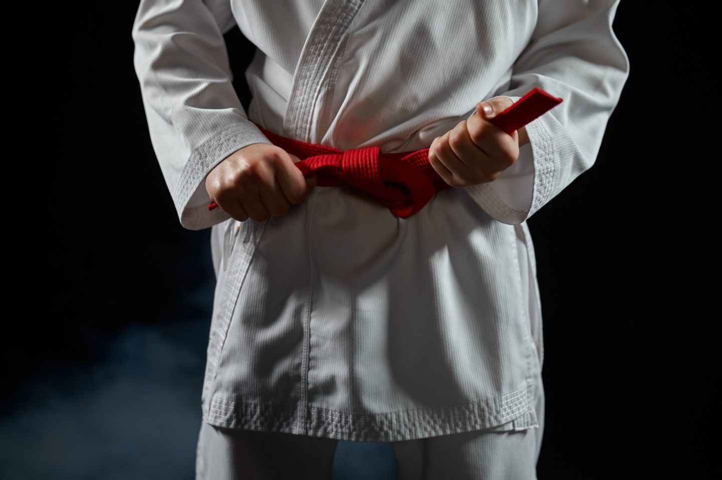 Karate fighter in white kimono having red belt