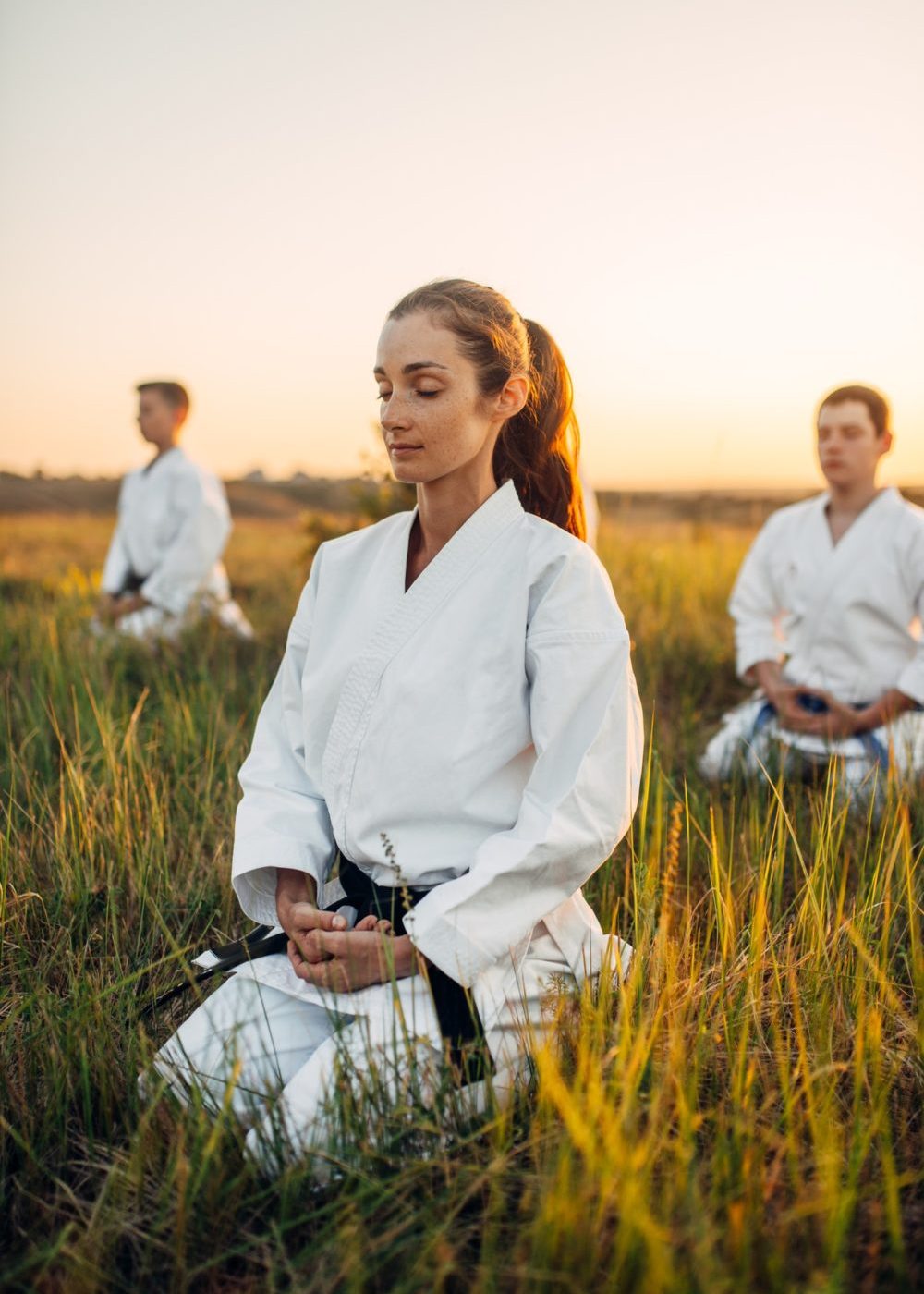 Karate class meditates on training in summer field