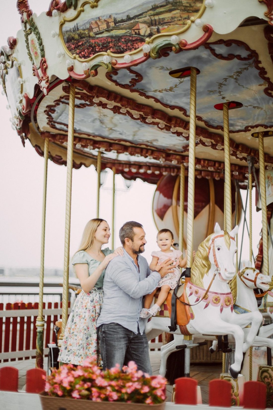 a young family with a baby girl having fun in an amusement Park on a carousel
