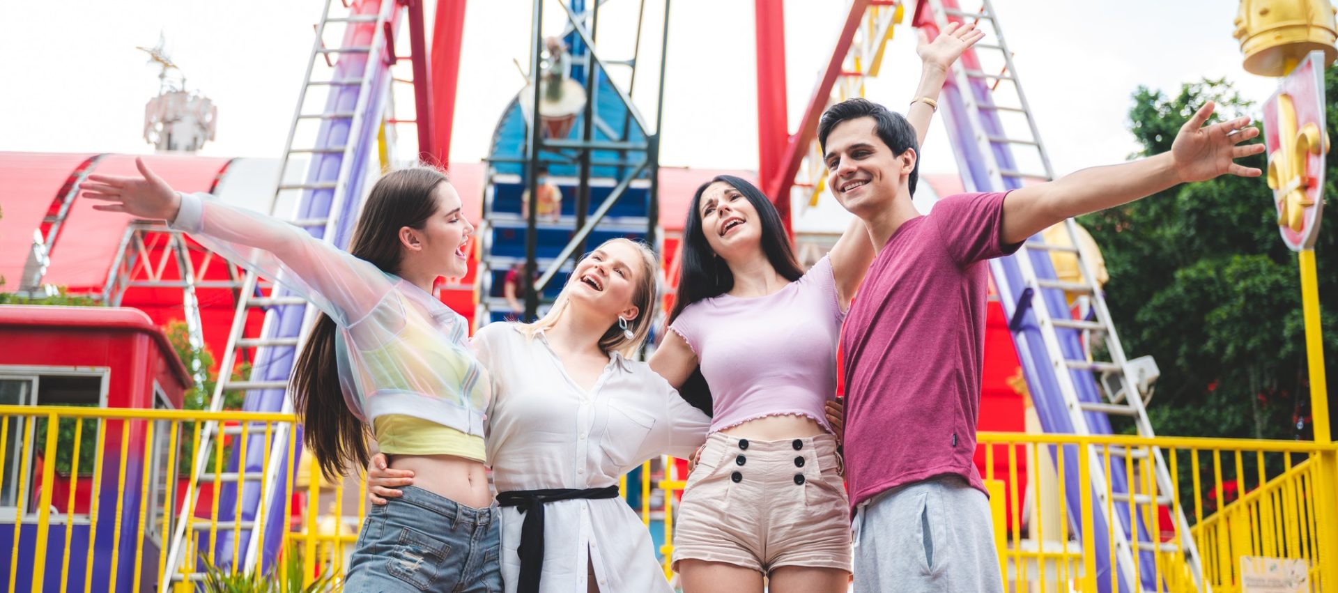 Group of happy best friends laughing and having fun at amusement park