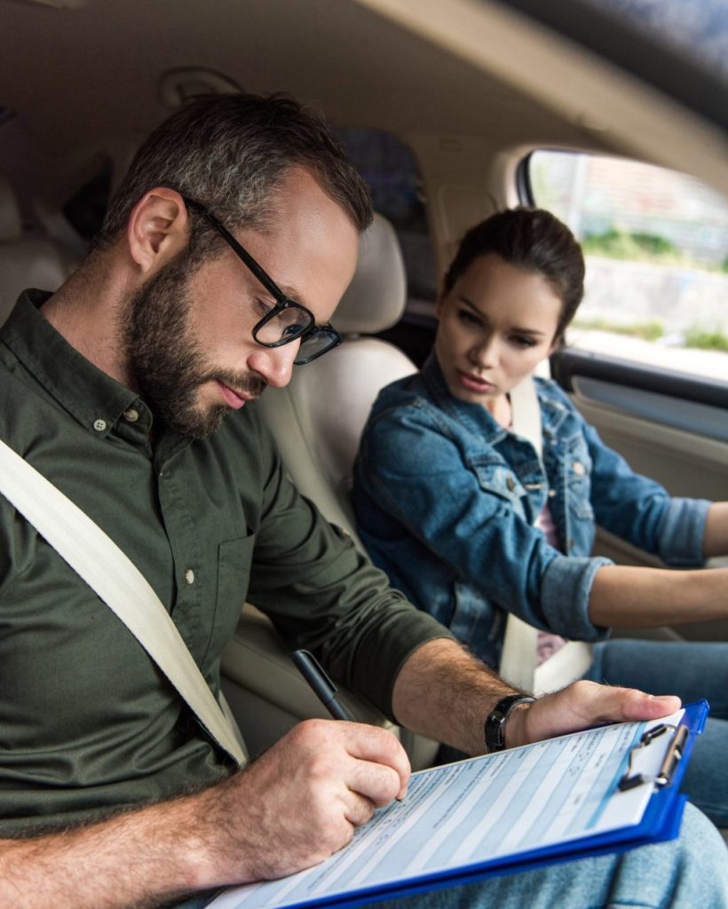 teacher writing something to clipboard during driving test