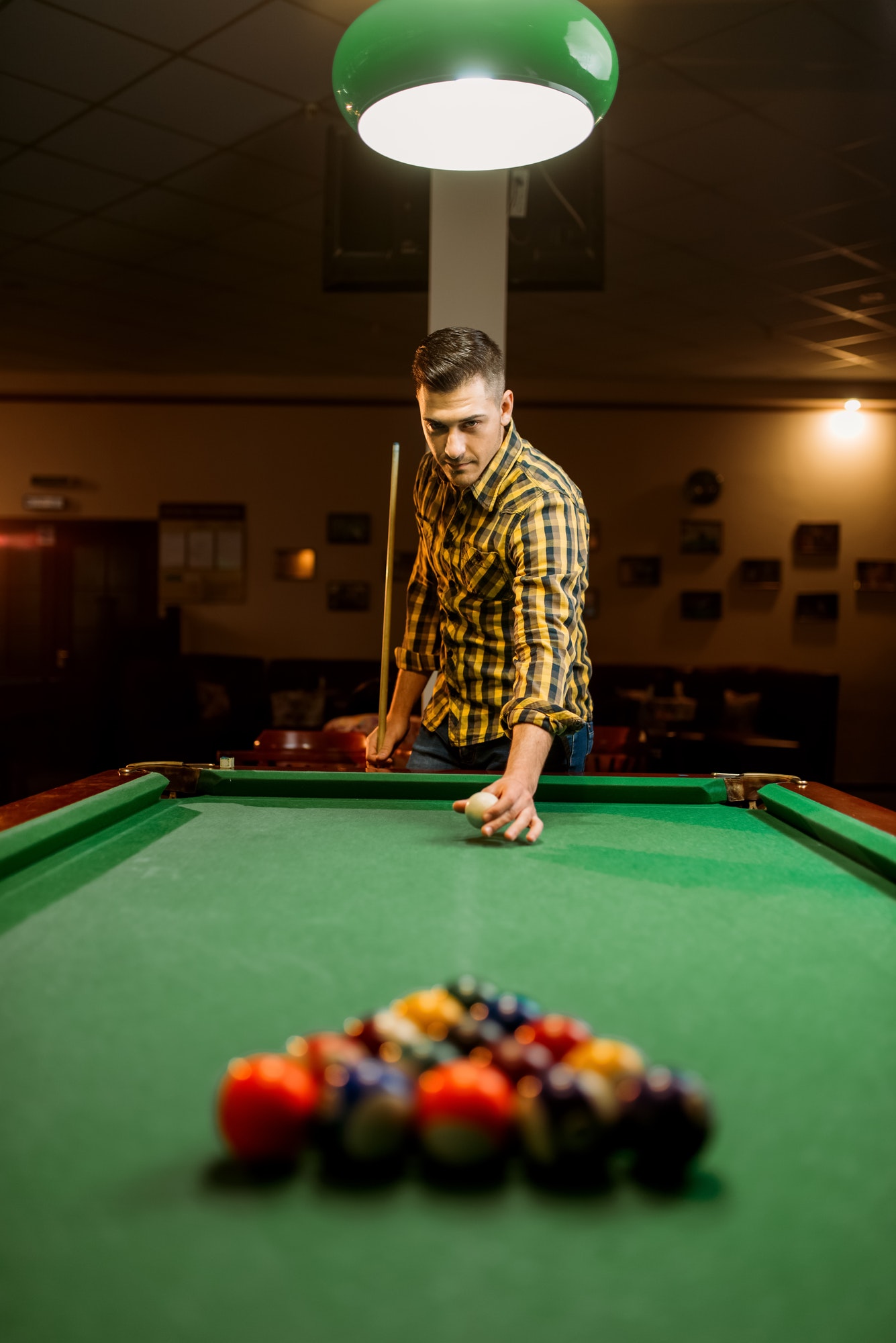 Male billiard player with cue aiming at the table