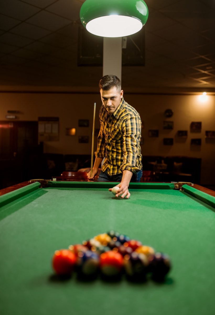 Male billiard player with cue aiming at the table