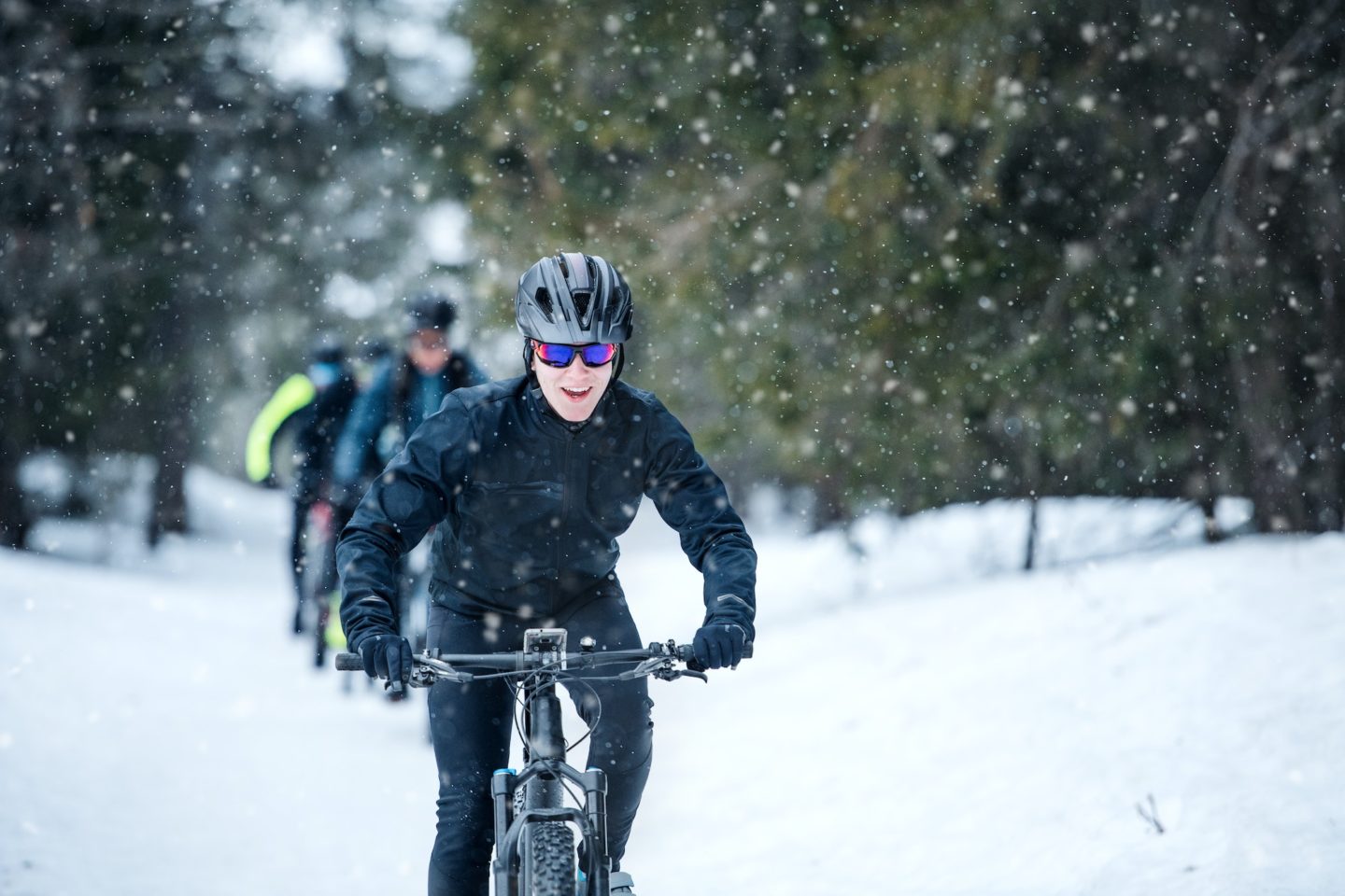 Group of mountain bikers riding on road outdoors in winter.