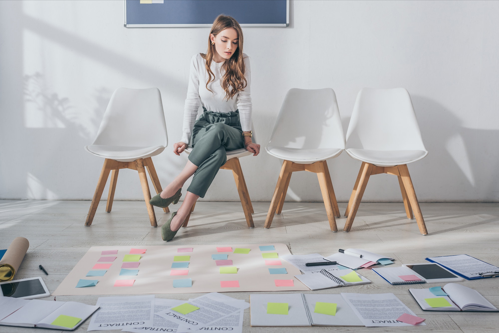 attractive scrum master sitting on chair near sticky notes on floor