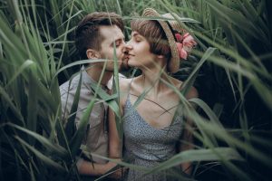 Stylish rustic bride and groom embracing in windy high reed