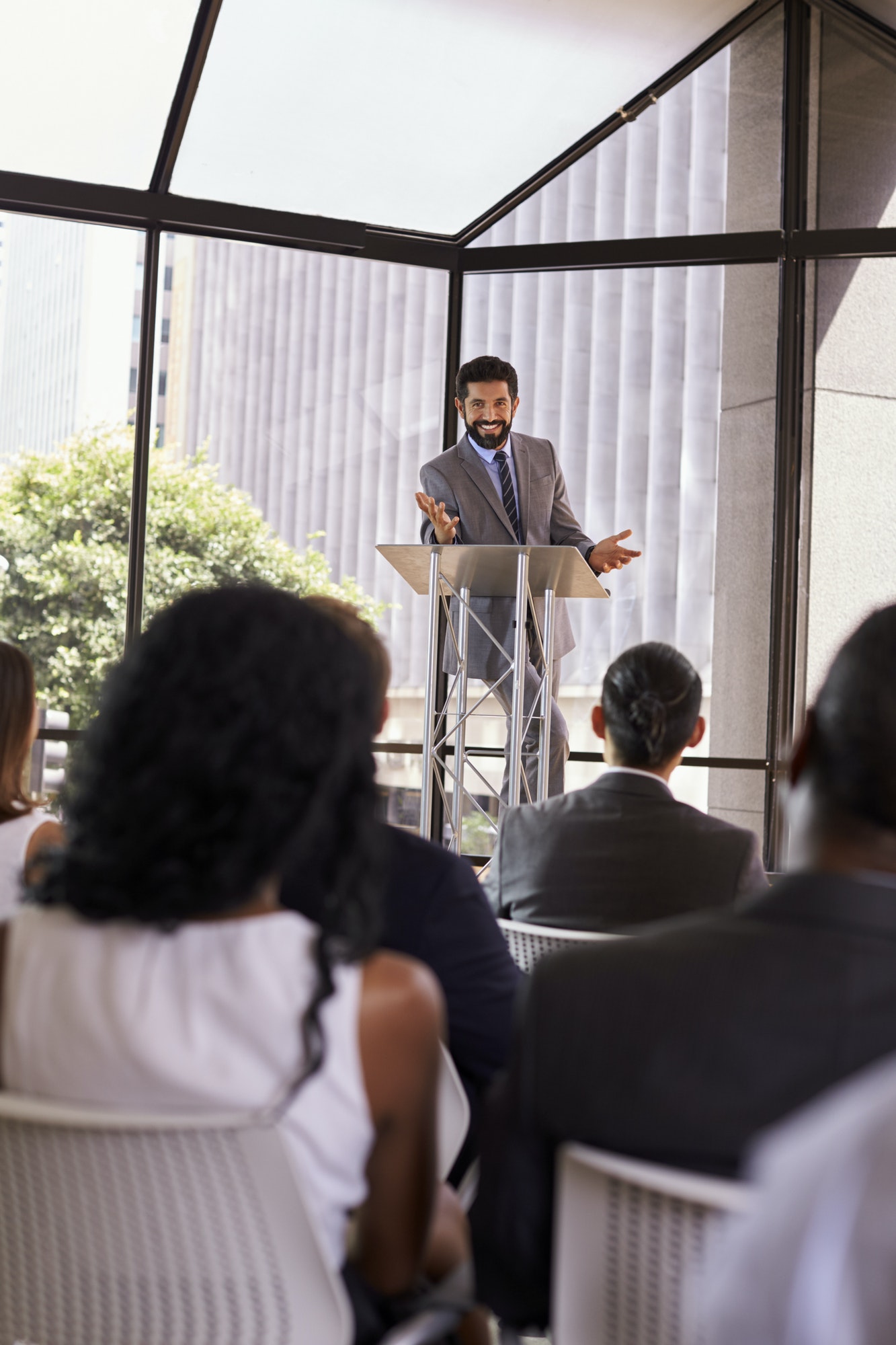 Hispanic man presents business seminar to audience, vertical