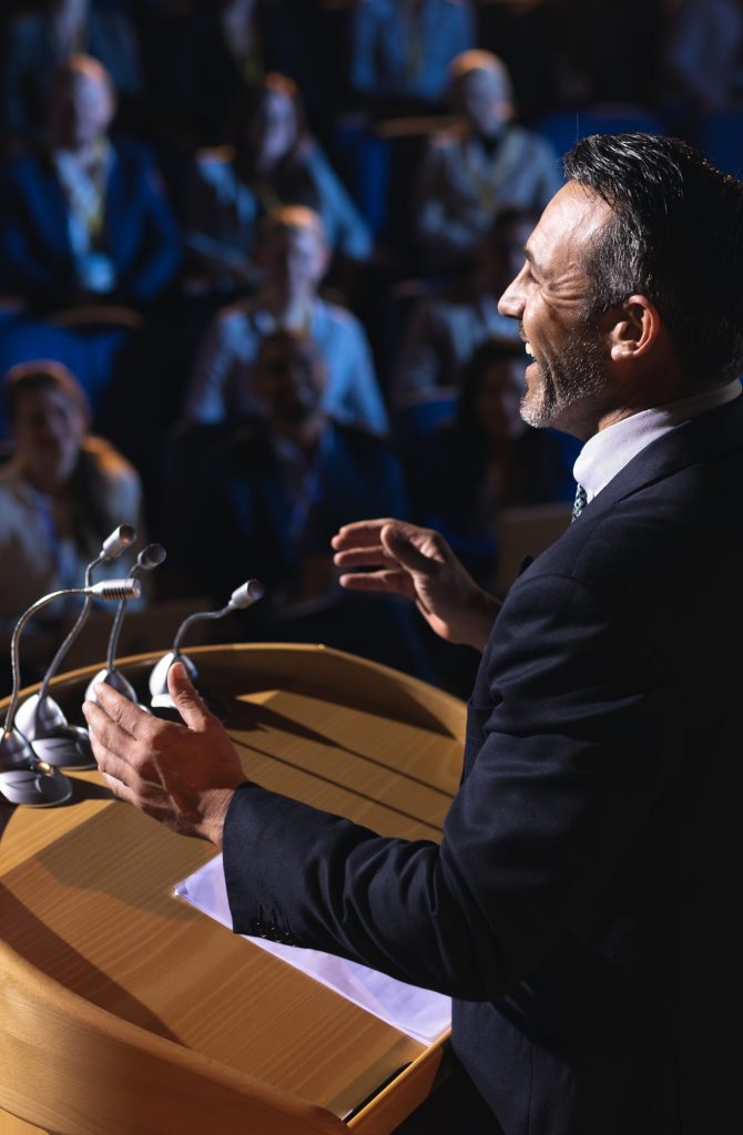Side view of Caucasian businessman standing and giving presentation in the auditorium