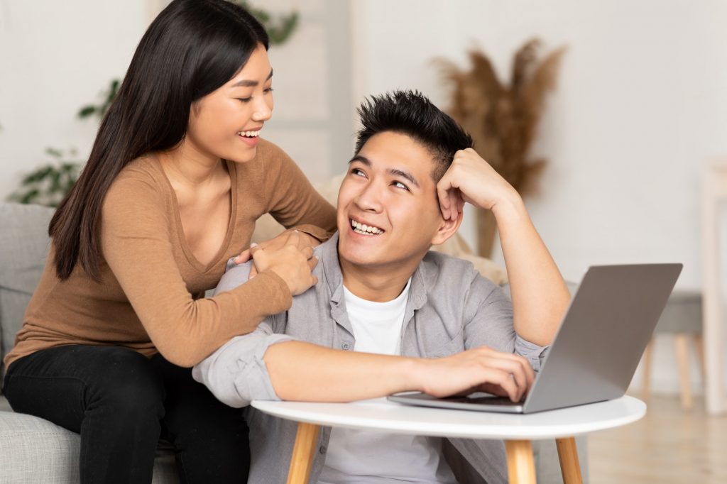 Young asian couple watching video on laptop