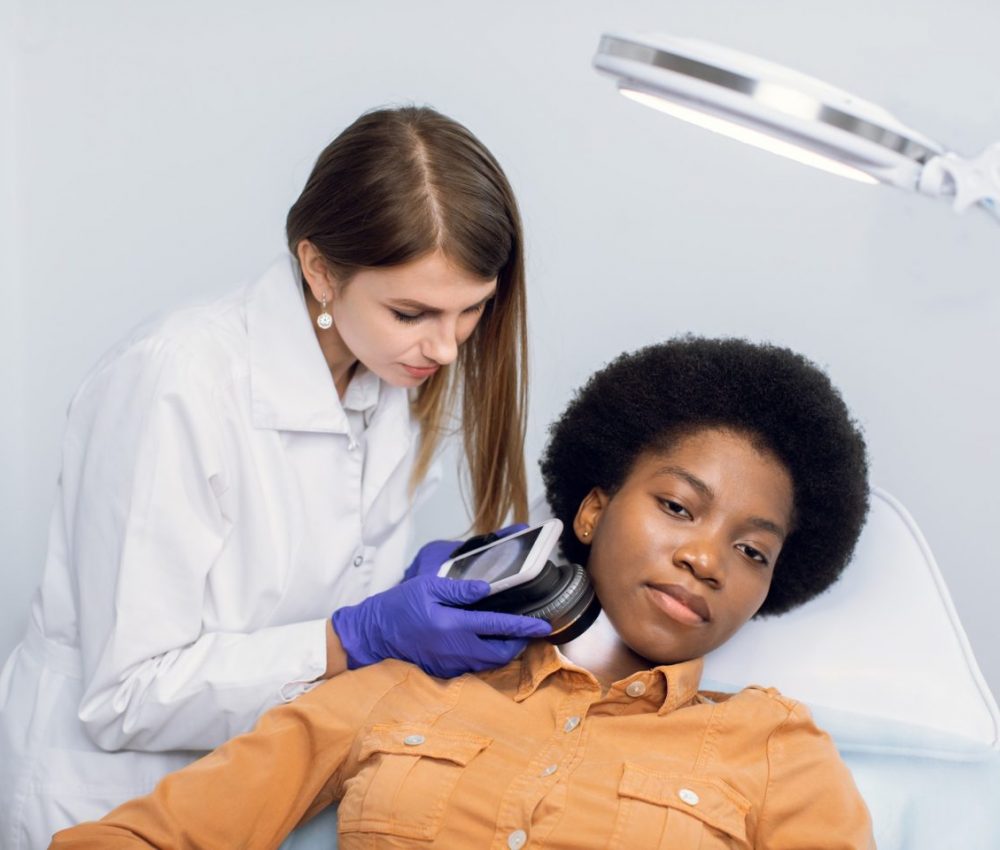 Young African American woman client lying on the couch in modern dermatology clinic, having face
