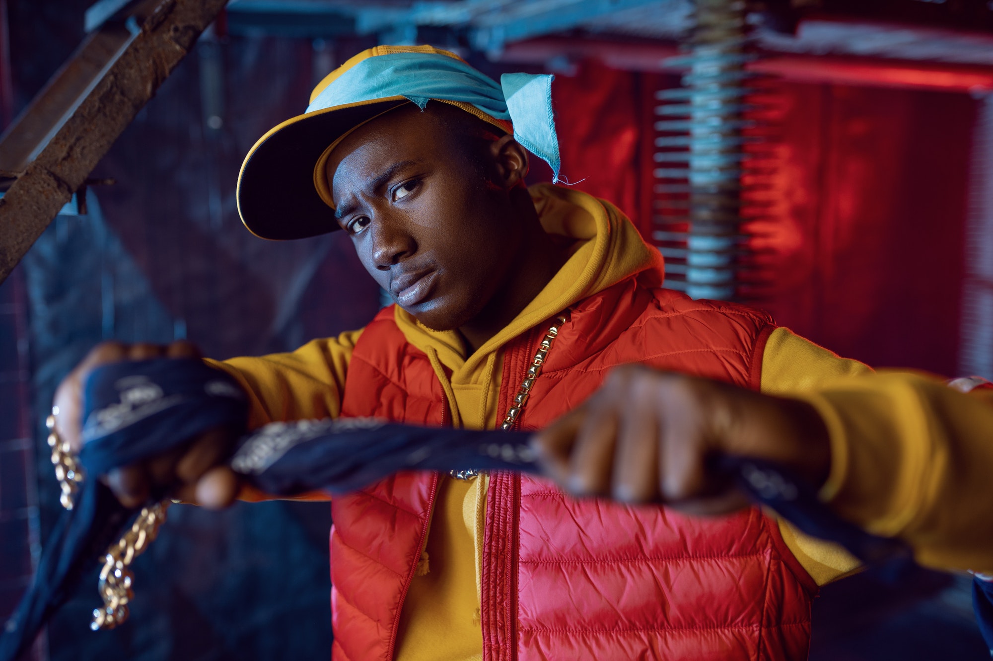 Stylish rapper in yellow hoodie posing in studio