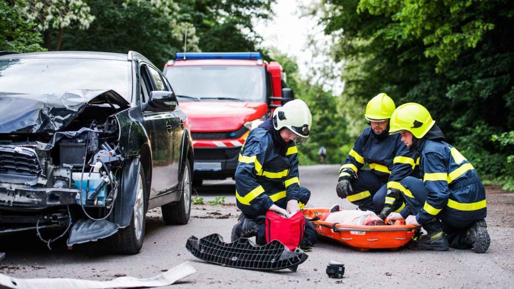 Firefighters helping a young injured woman after a car accident.