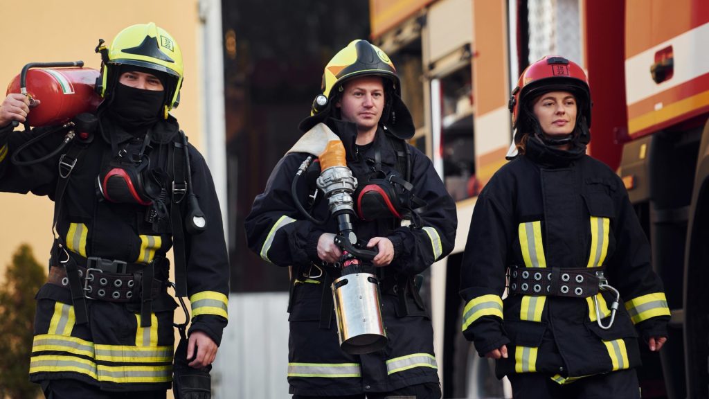 Group of firefighters in protective uniform that outdoors near truck