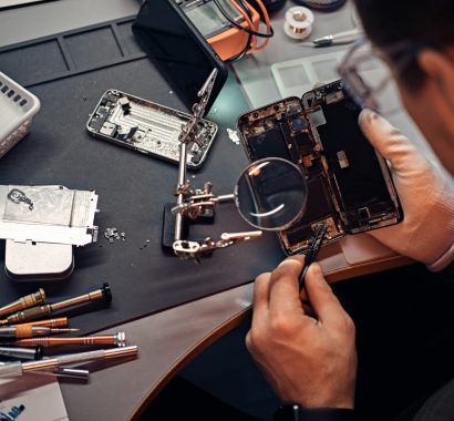 Technician carefully inspect the internal parts of the smartphone in a modern repair shop
