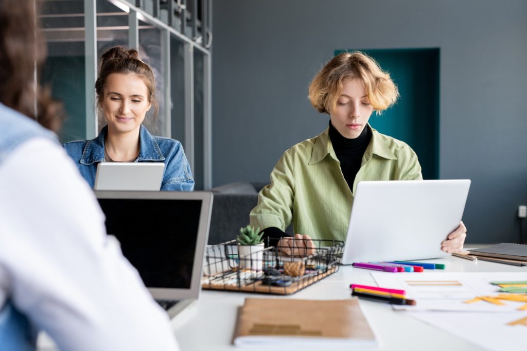 Two young creative female programmers working over new software in office