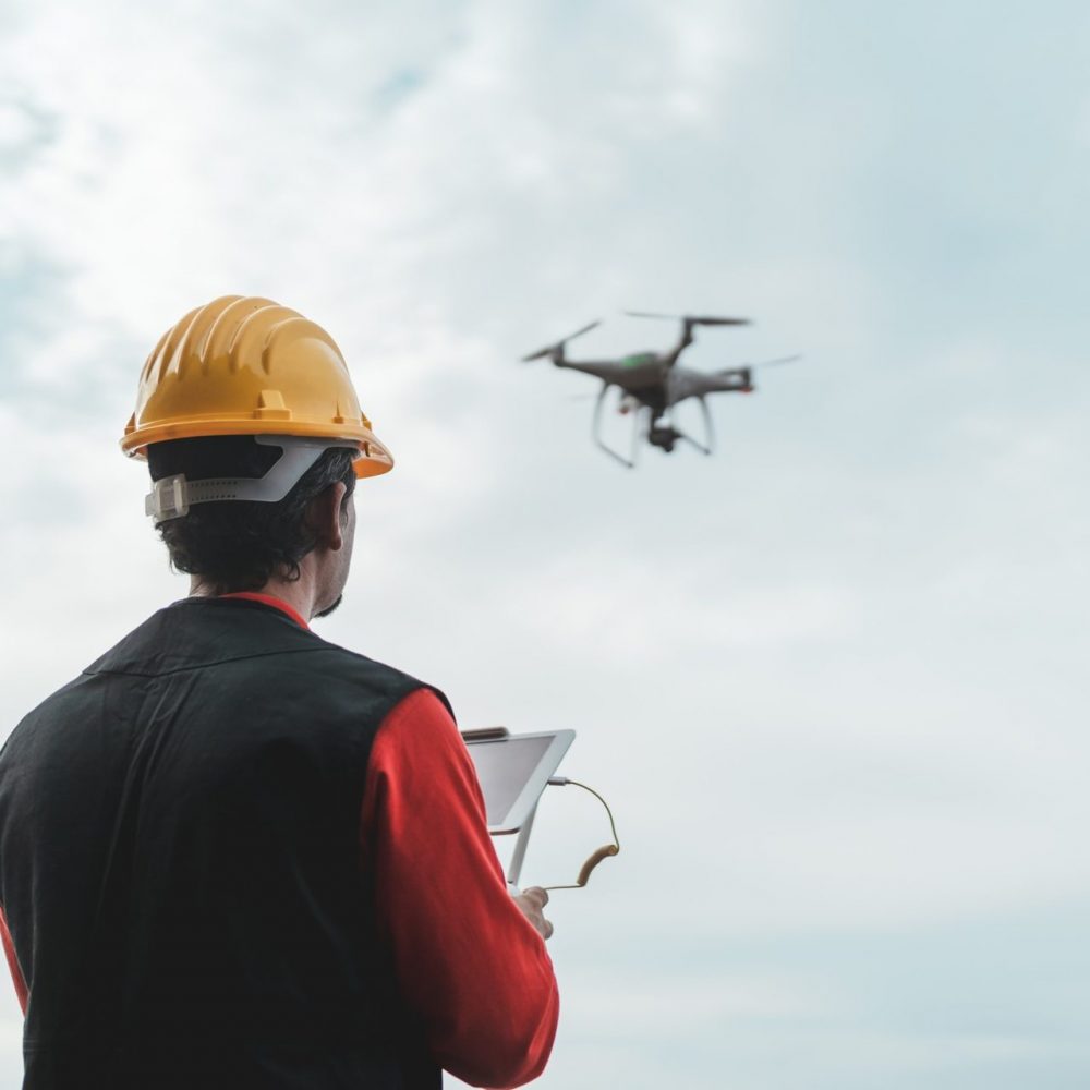 Male engineer monitoring construction site with drone - Technology and industrial concept