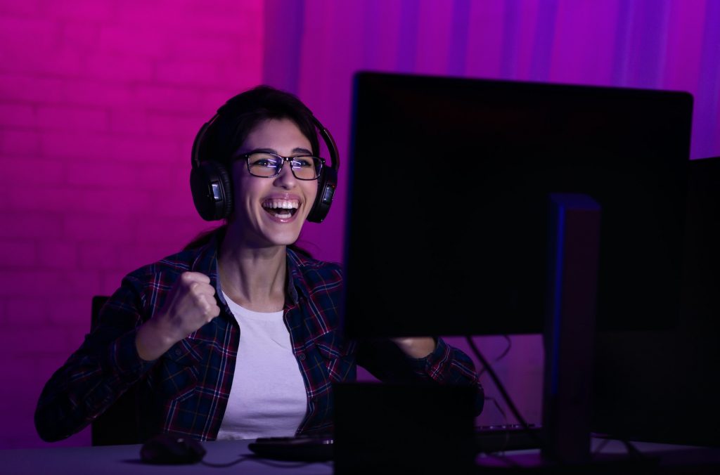 Female gamer win game, wearing headphones and rejoicing