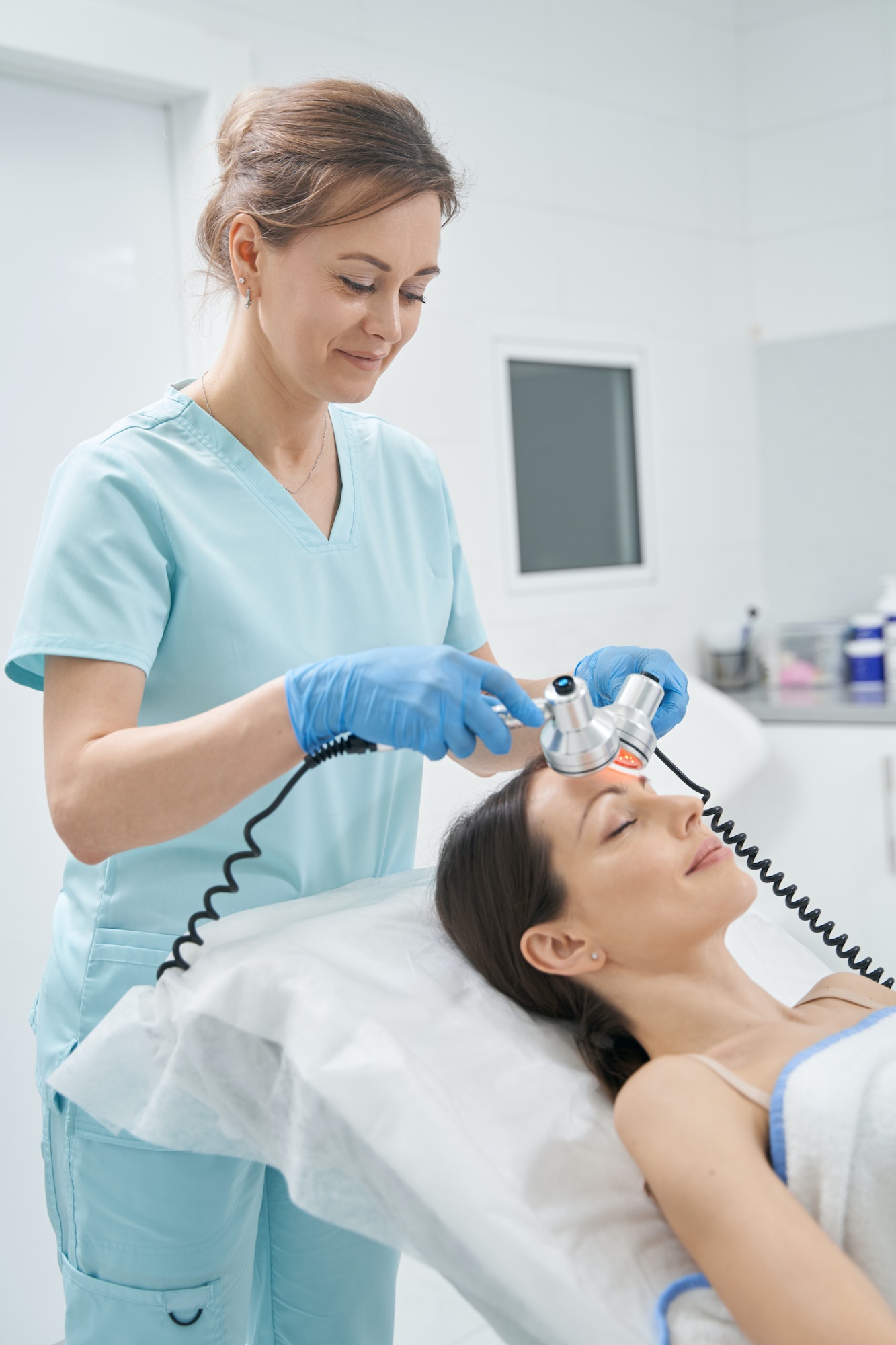 Cosmetologist performing radiofrequency facial treatment in clinic