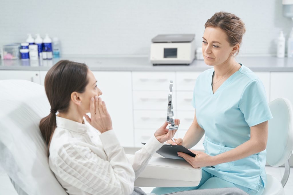 Woman having consultation with doctor in cosmetology clinic
