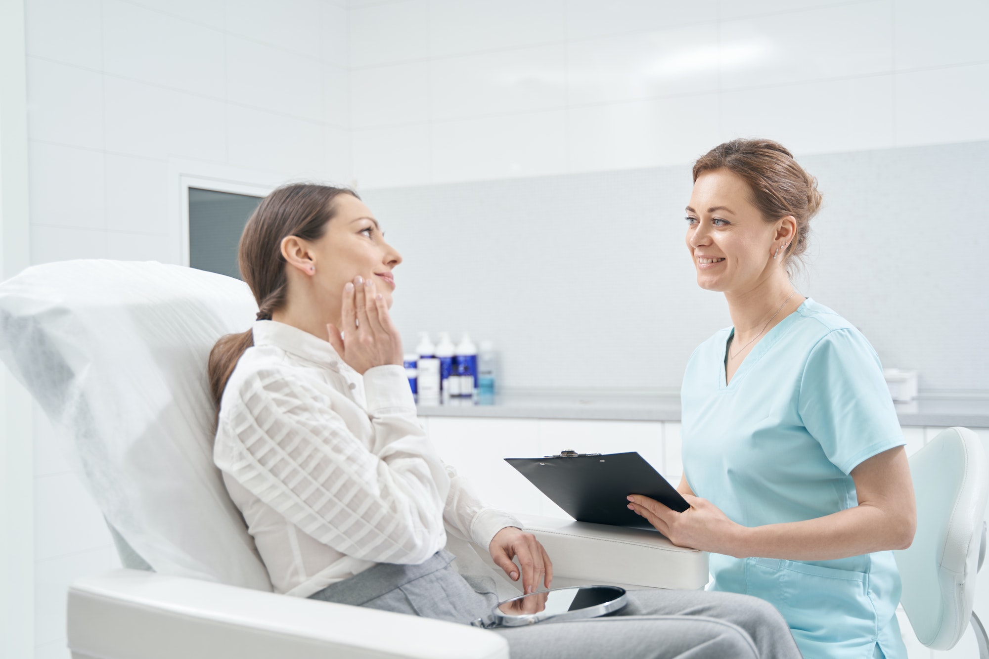 Woman talking with doctor beautician in cosmetology clinic