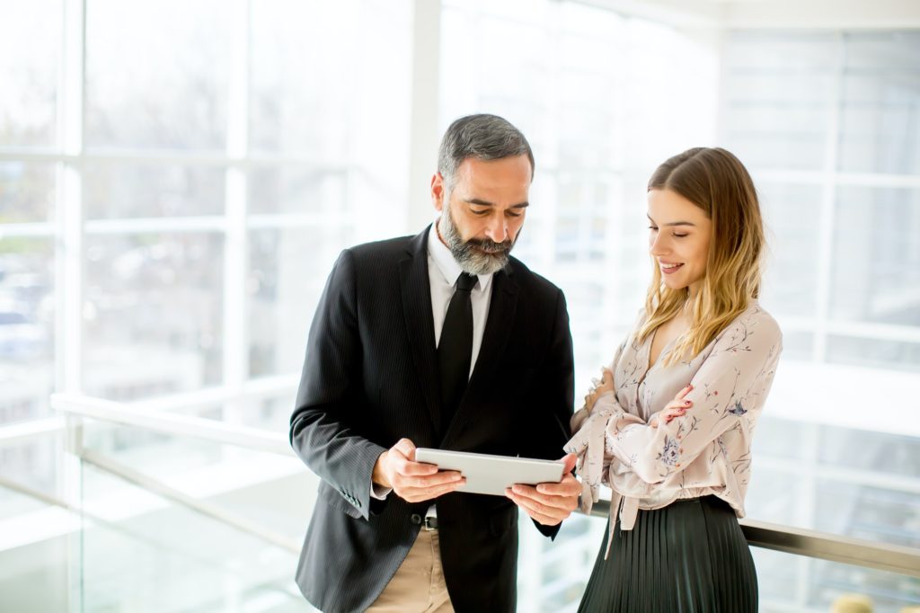 Senior businessman and young businesswoman with tablet in office