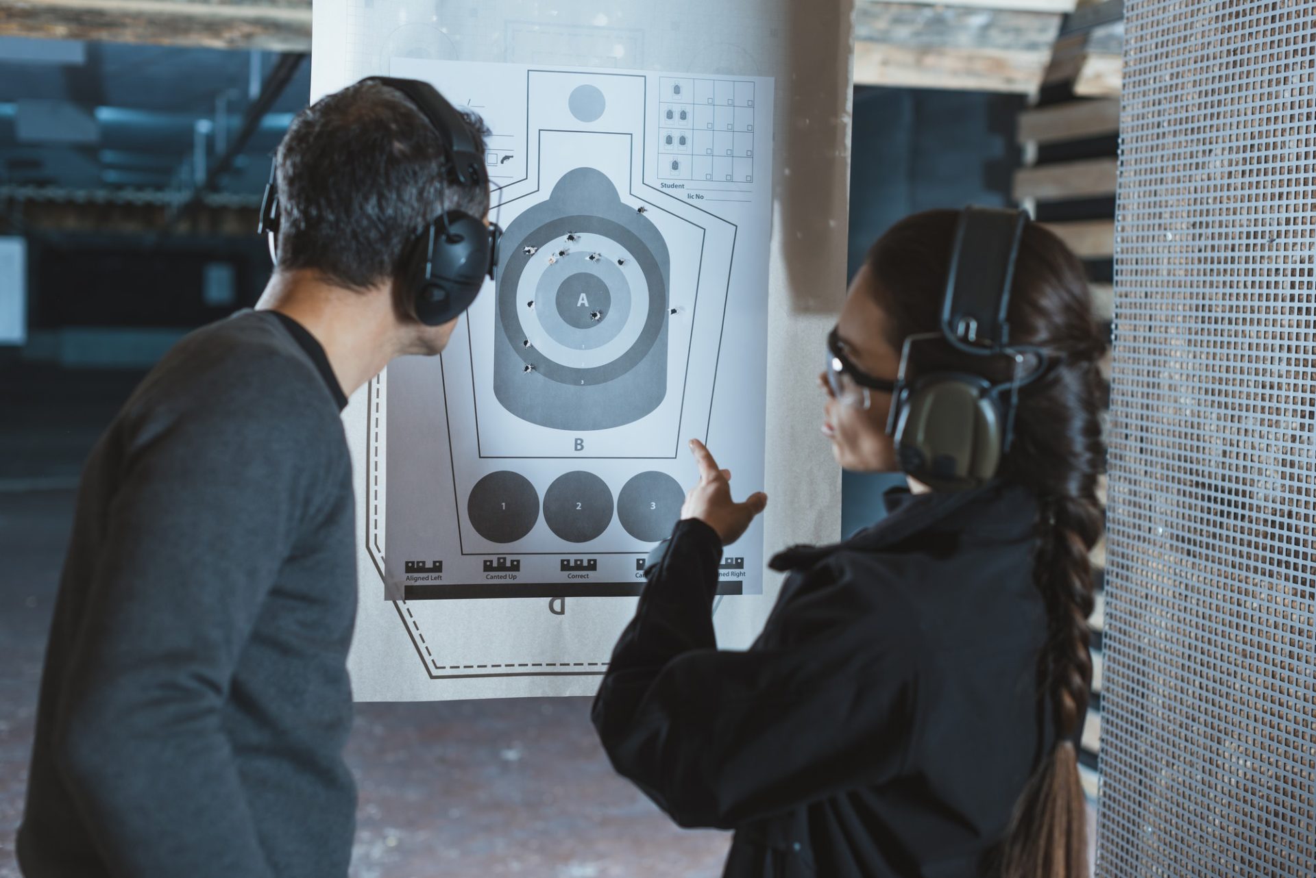 shooting instructor pointing on used target in shooting range