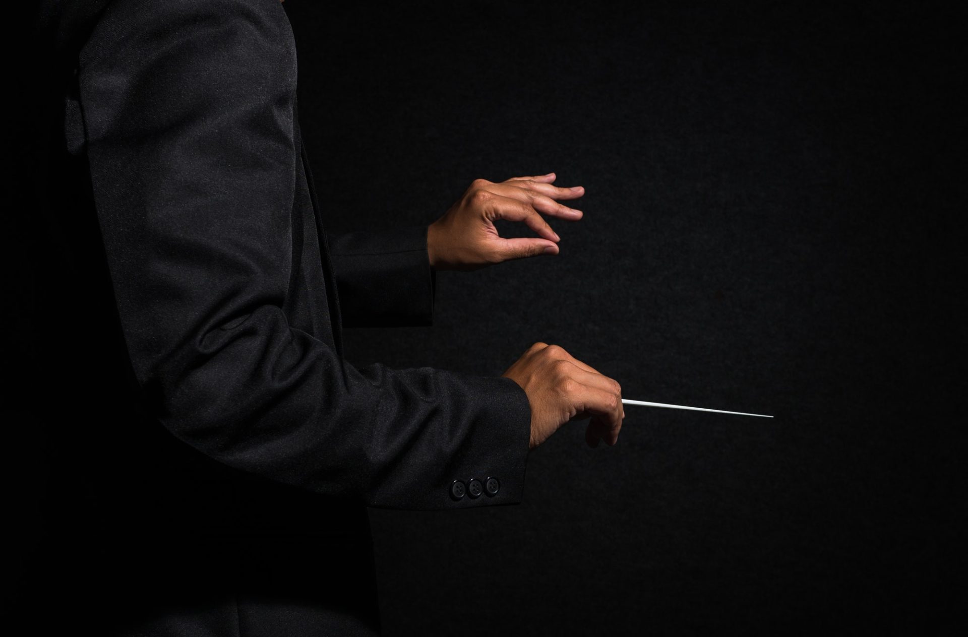 Orchestra conductor hands, Musician director holding stick on dark background