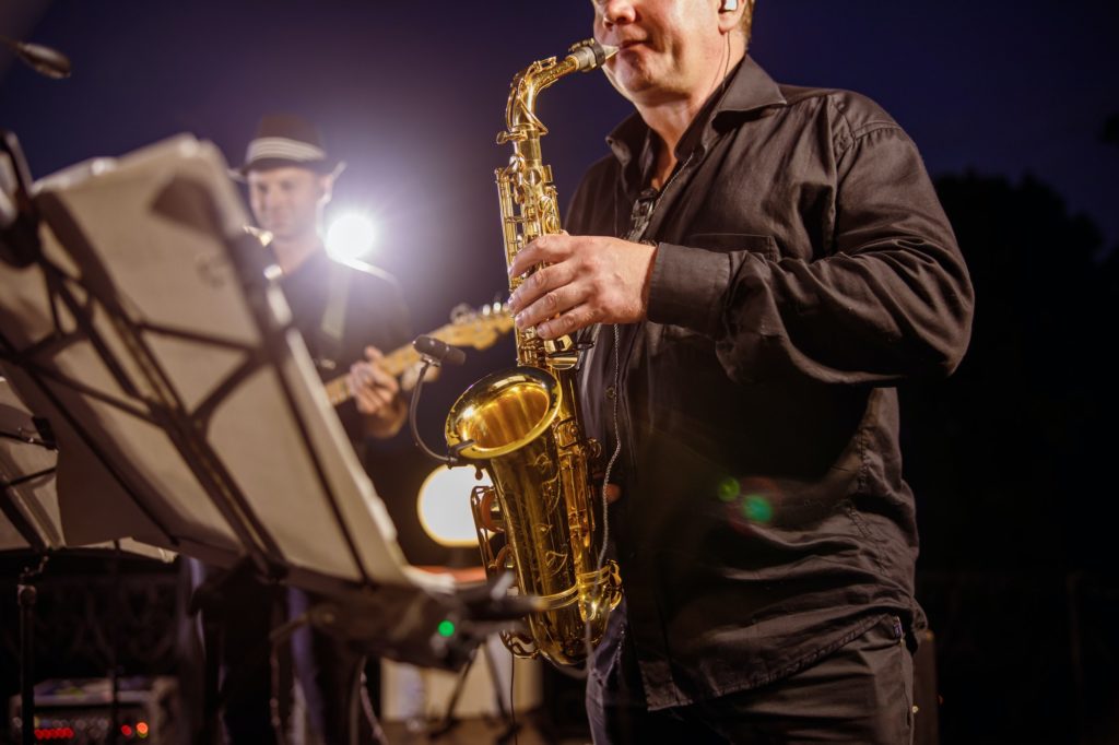 Saxophone player playing in orchestra at night outdoor concert