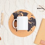 Mockup with white mug, glasses, watch, pen, notebook and globe print on white knitted background