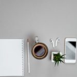Top view of stationery and telephone, coffee on grey desktop background. Business concept
