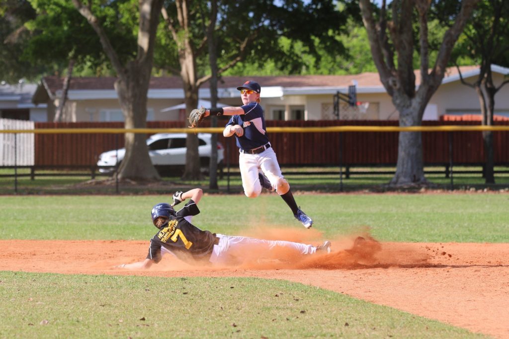 A baseball game where the second baseman is in the air while making a play