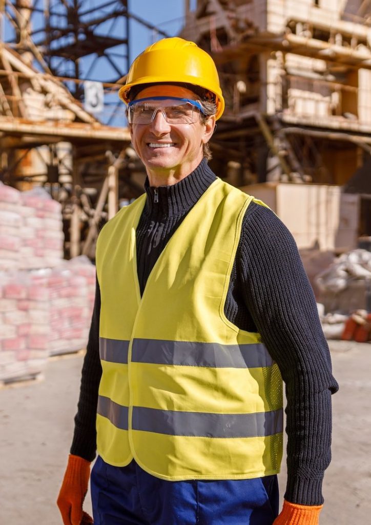 Joyful man construction worker standing outdoors at industrial site