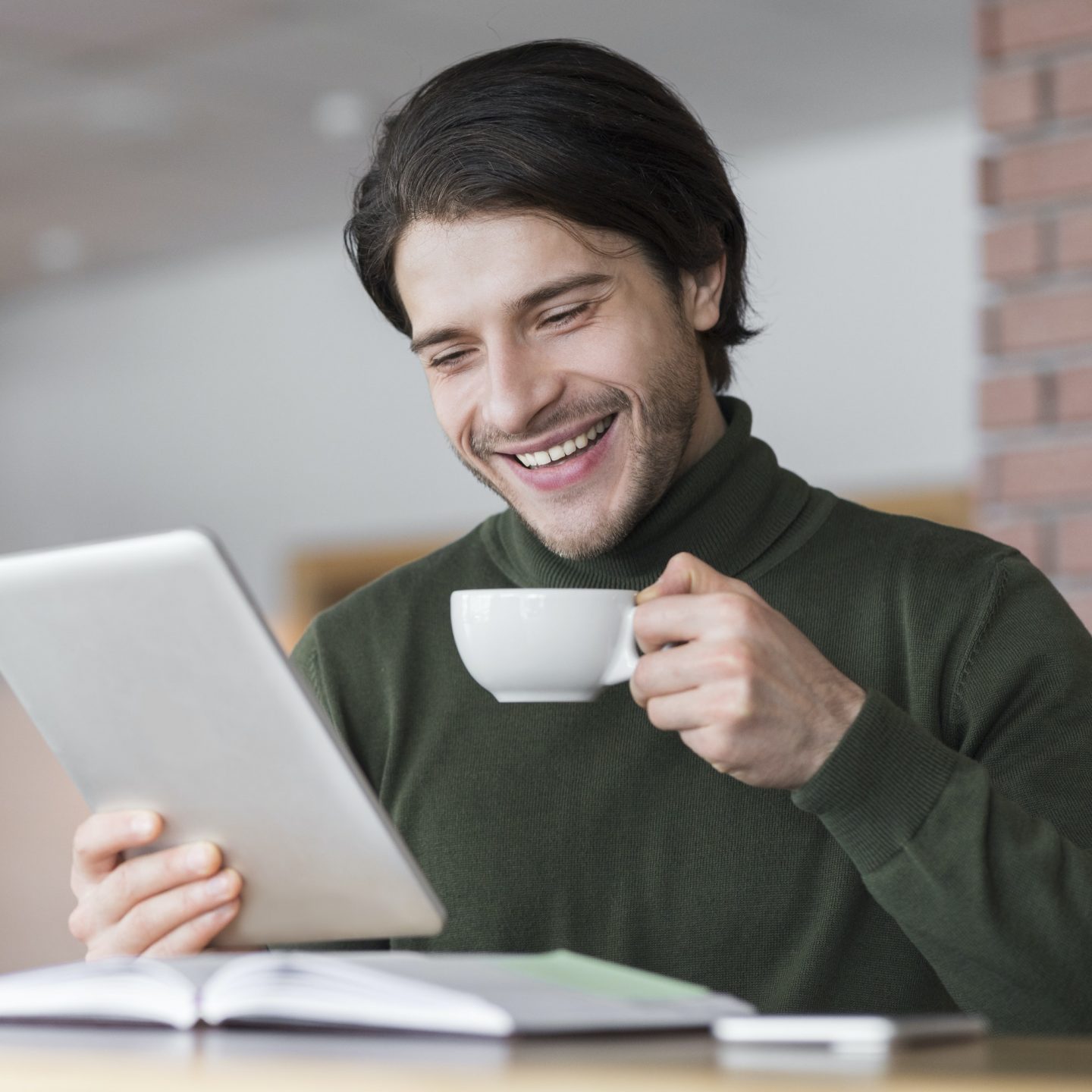 Young successful businessman checking emails while having morning coffee