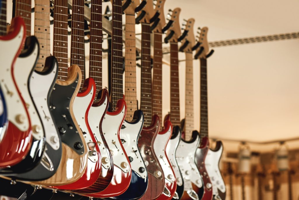 Buying electric guitar. Stand with various colorful electric guitars in music shop. Musical