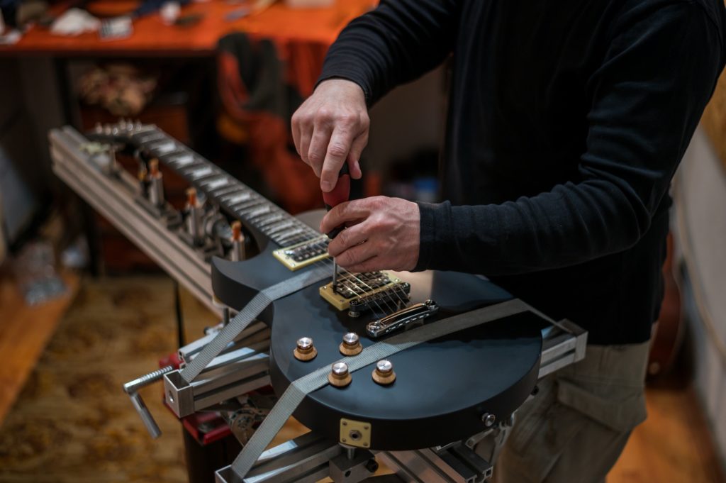 Electrical guitar in repair service shop with a hands of a guitar luthier