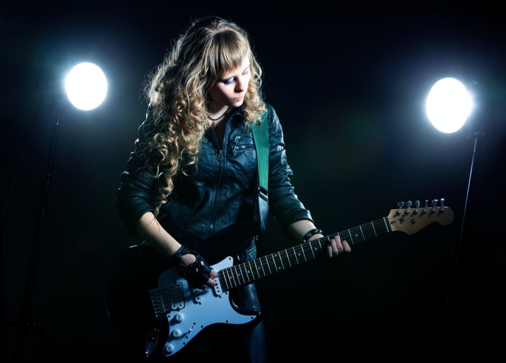 Girl guitarist with spotlights behind her