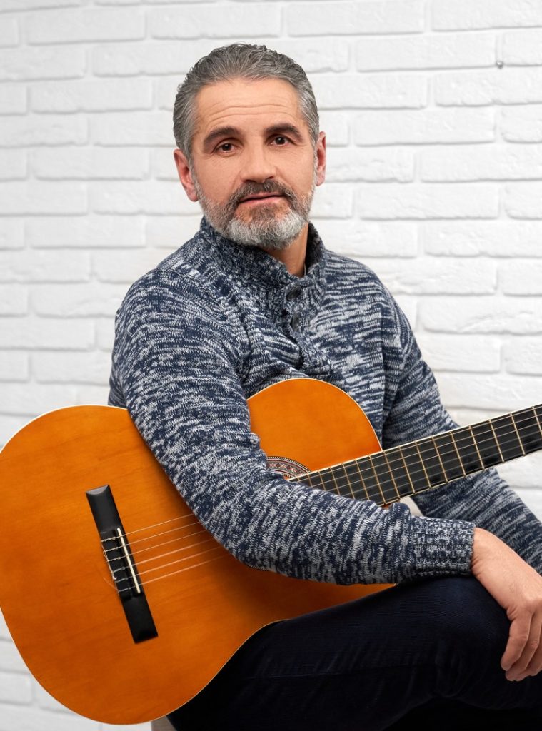 Mature man posing in studio with guitar