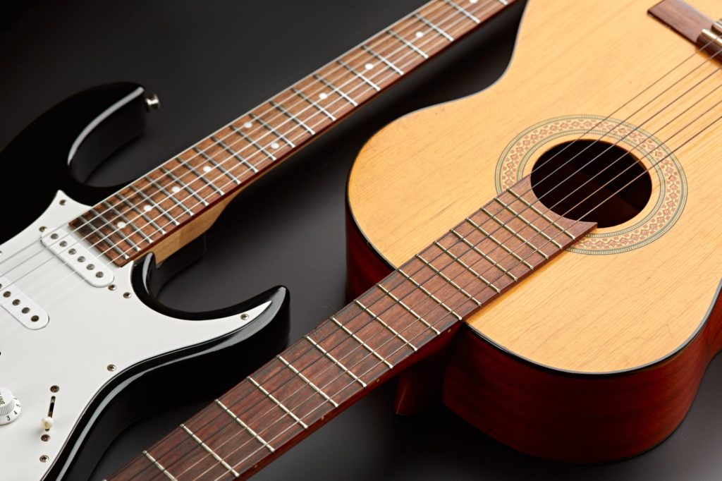 Modern electric and retro acoustic guitars closeup