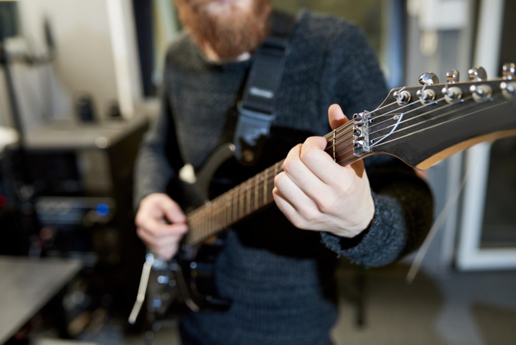 Skilled man playing electric guitar in studio