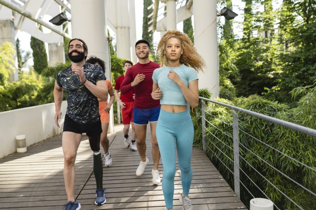 Multiracial group of runners running in an park with plants.