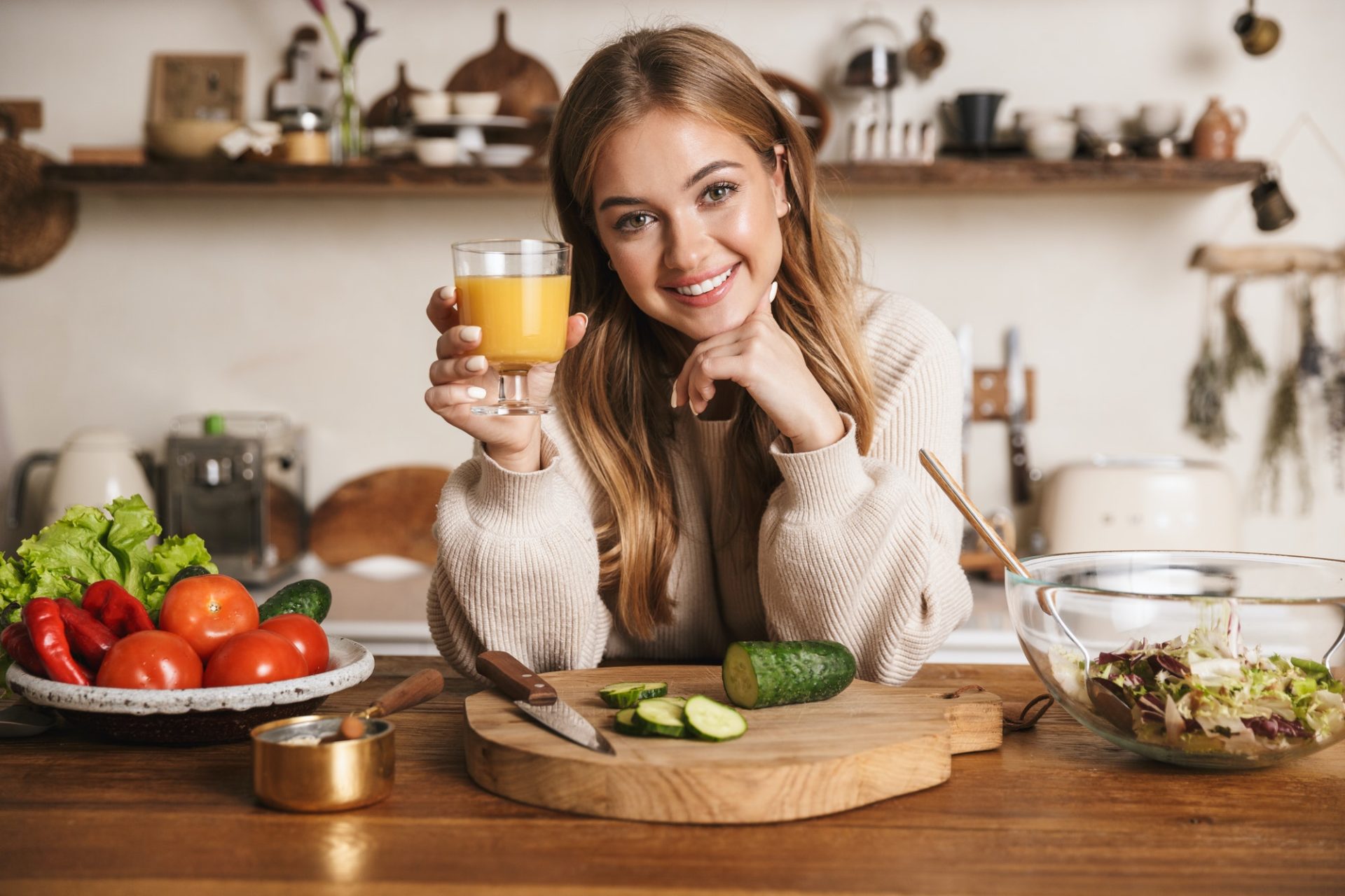 Image of smiling cute woman drinking juice while making lunch