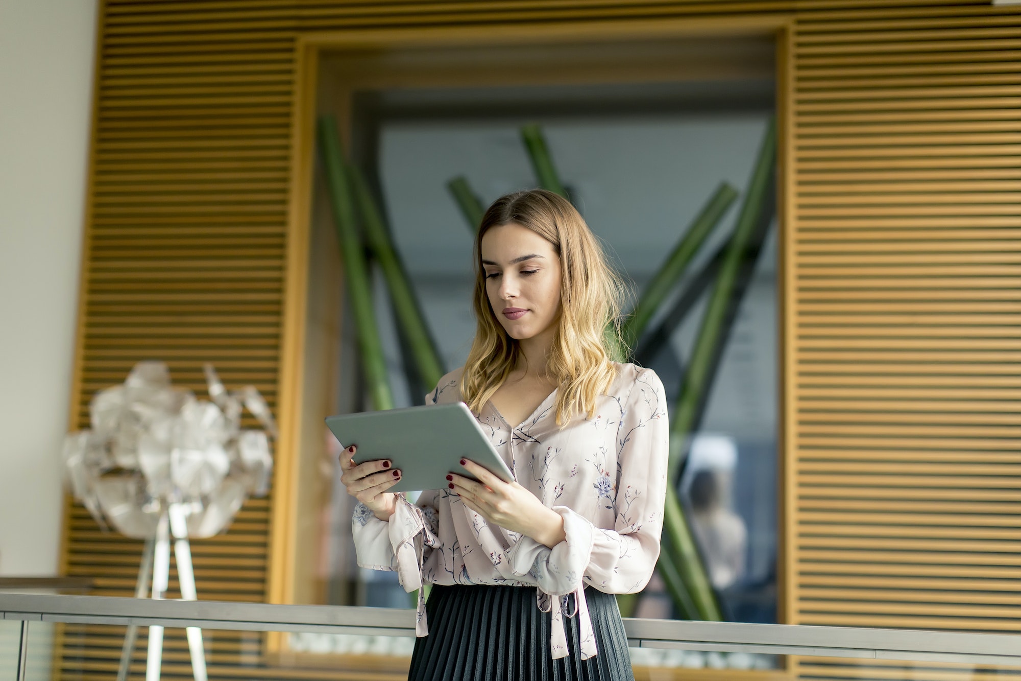 Attractive businesswoman using a digital tablet while standing in the office