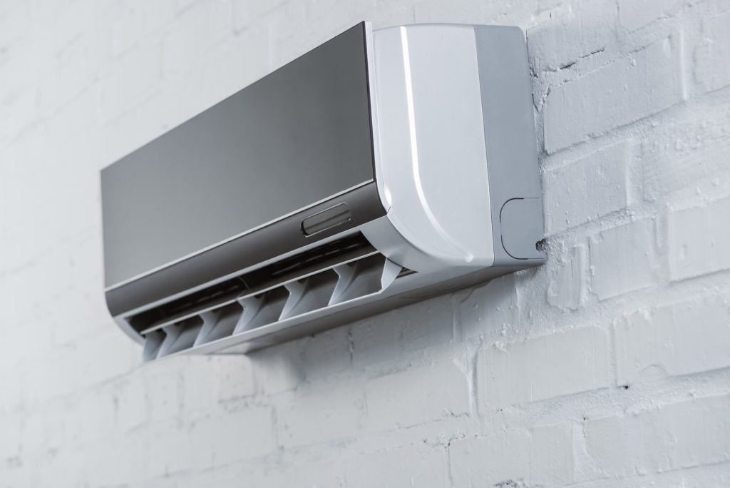 close-up shot of modern air conditioner hanging on white brick wall