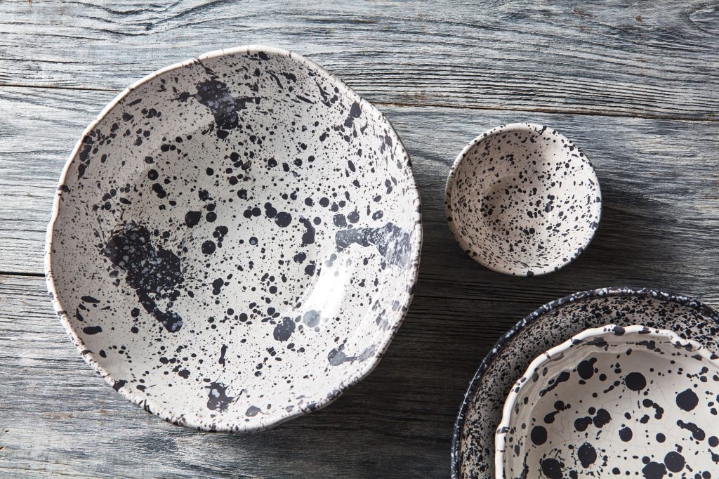 Decorative pottery - bowls, plates covered with glazed on a gray wooden background. Top view of
