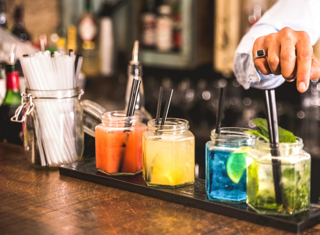Bartender hand at multicolored fashion drinks