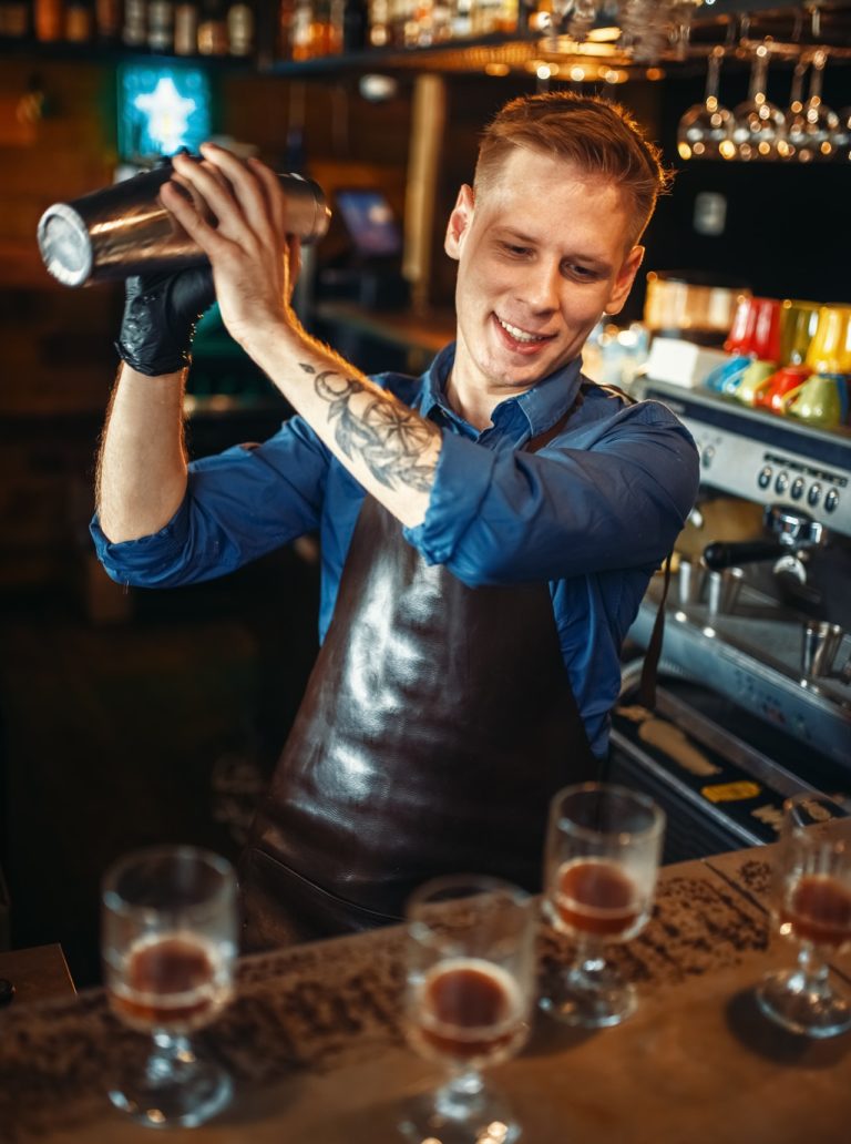 Bartender works with shaker at the bar counter
