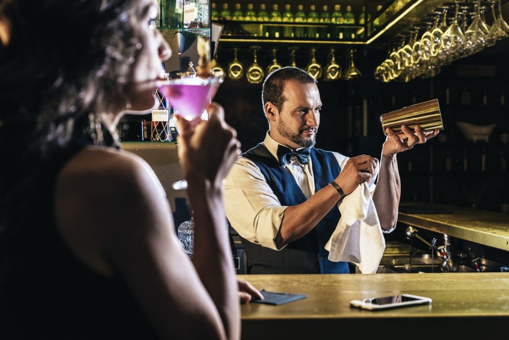 Handsome bartender serving cocktail to beautiful woman