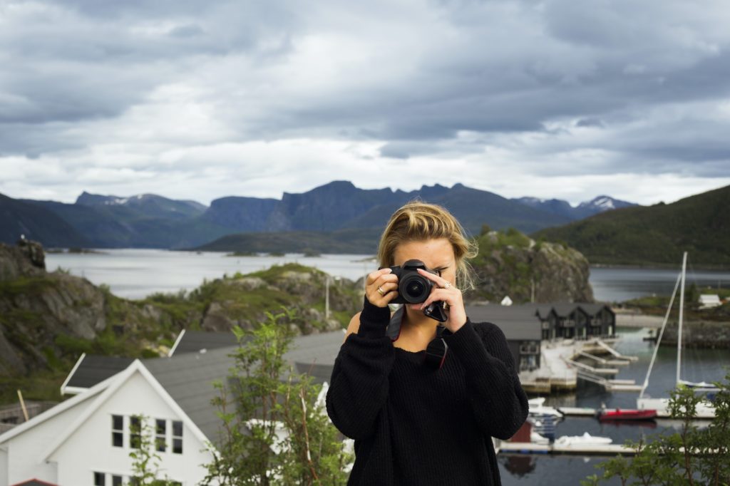 Woman photographing through digital camera against mountains