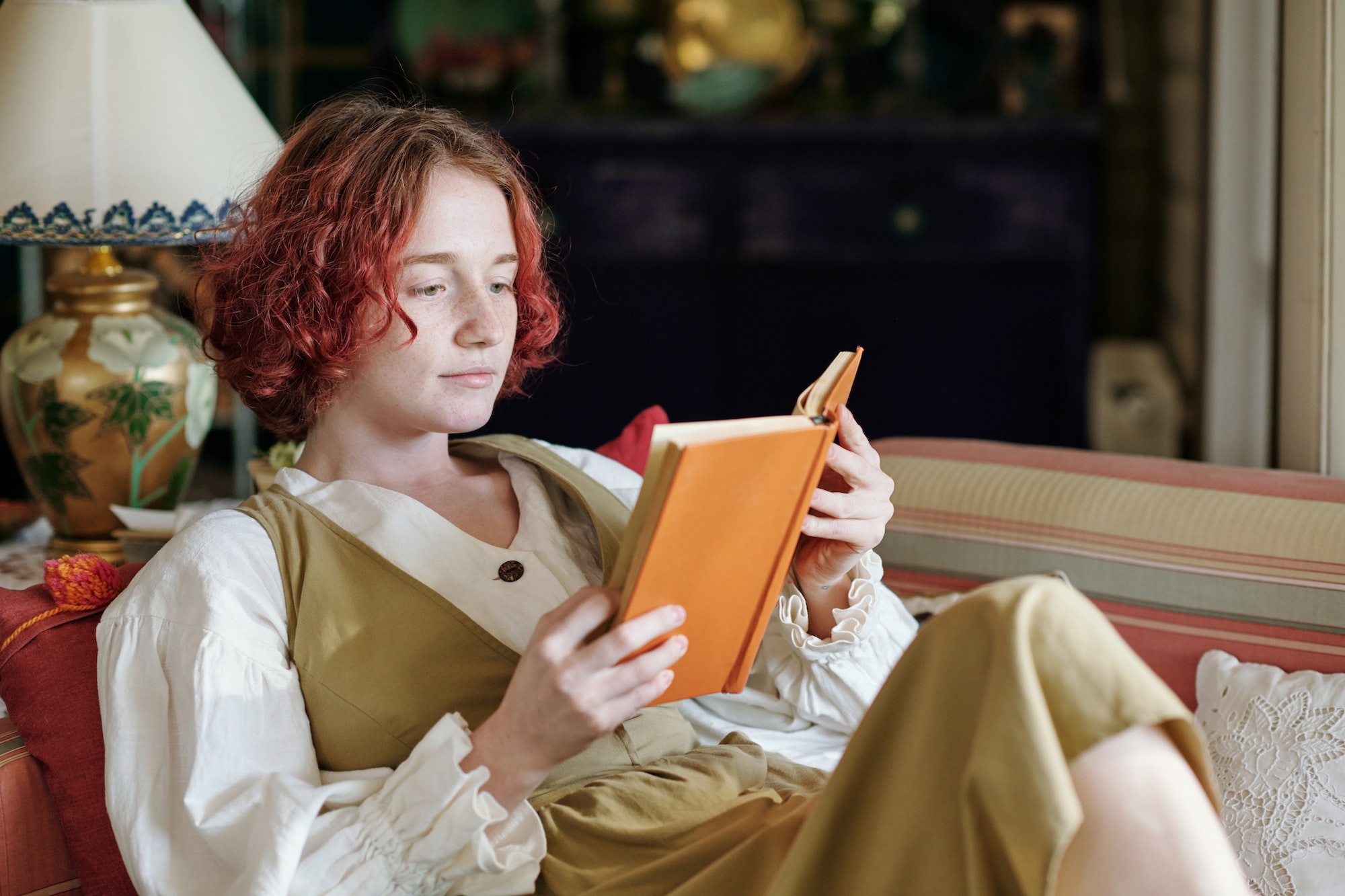 Young woman in smart casualwear reading novel while relaxing on terrace