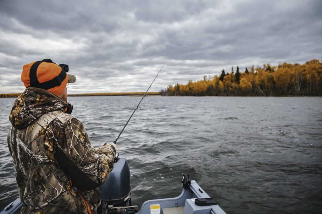A man fishing at the lake. Fishing from a boat autumn season.